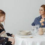 Mother and daughter sharing a happy meal together in a minimalistic dining room setting.